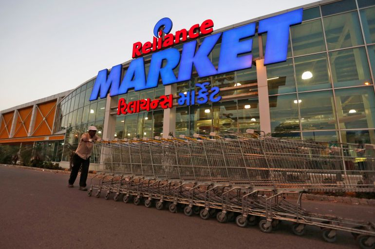 A man pushes grocery carts outside a Reliance Retail store