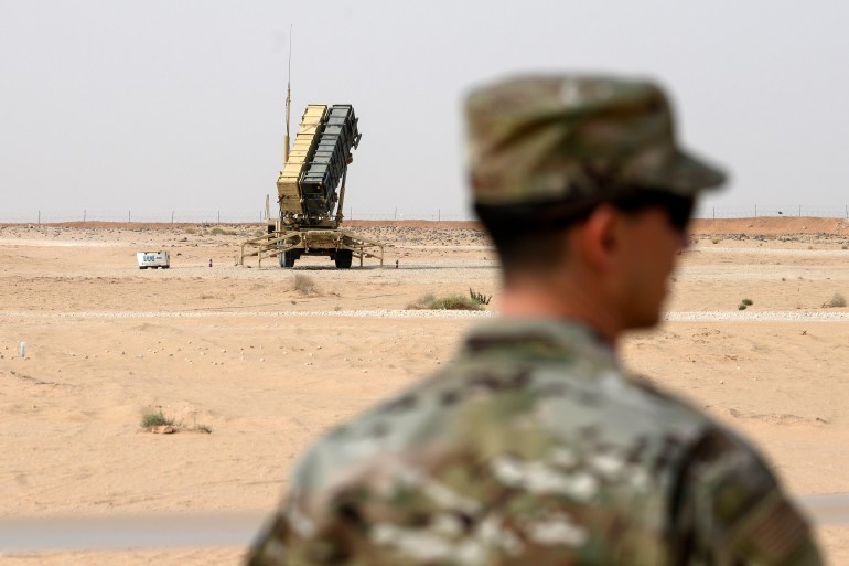 A soldier stands in the foreground with a US-made Patriot air-defence system