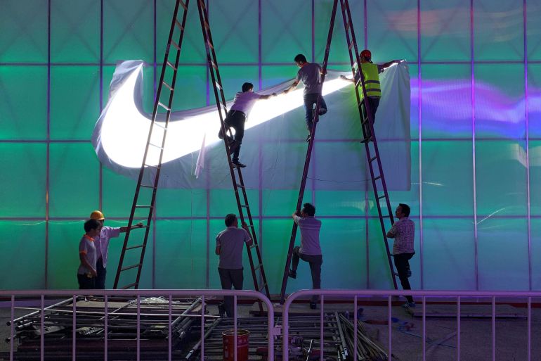 Workers install a Nike logo lamp outside the Wukesong Arena in Beijing, China
