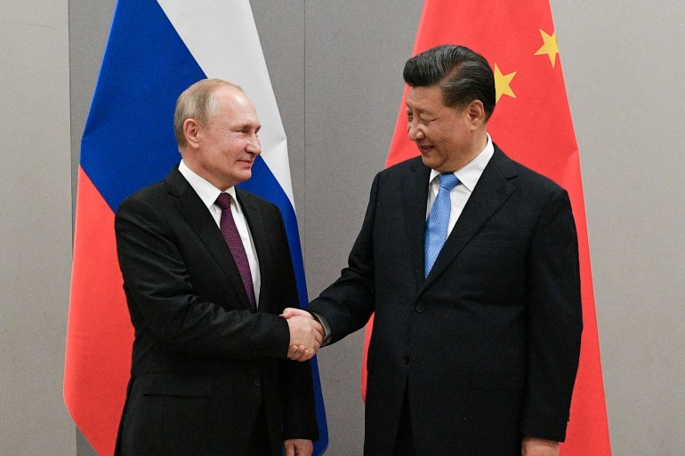 Putin and Xi shaking hands in front of Russian and Chinese flags