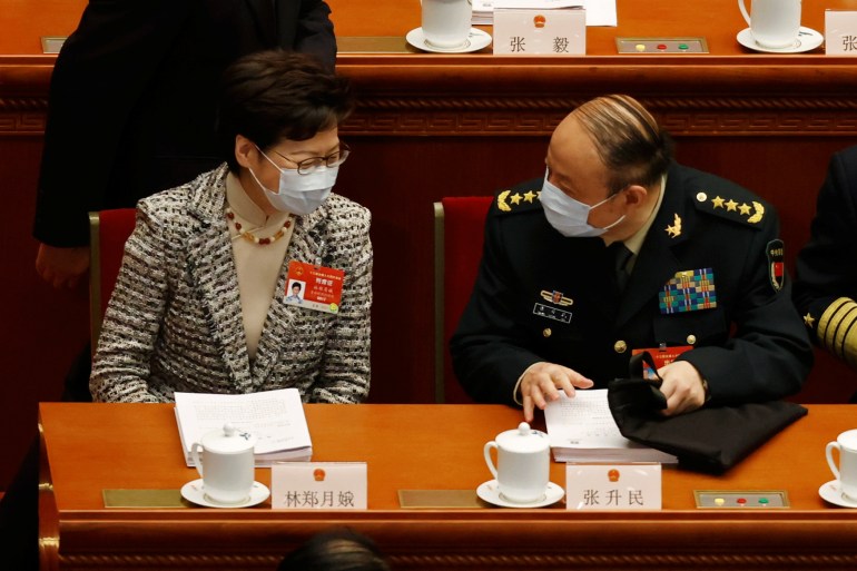 Hong Kong Chief Executive Carrie Lam chats with a military delegate ahead of the NPC's opening session. The parliament is discussing more changes to the territory's elections [Carlos Garcia Rawlins/Reuters]