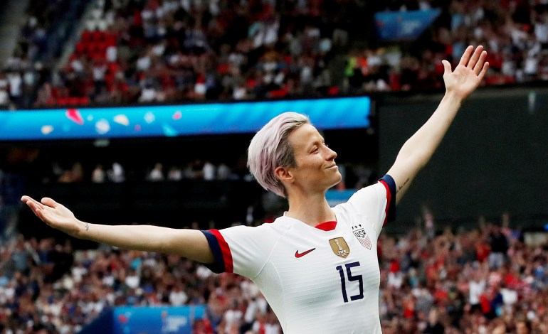 Megan Rapinoe holds her arms out after scoring a goal