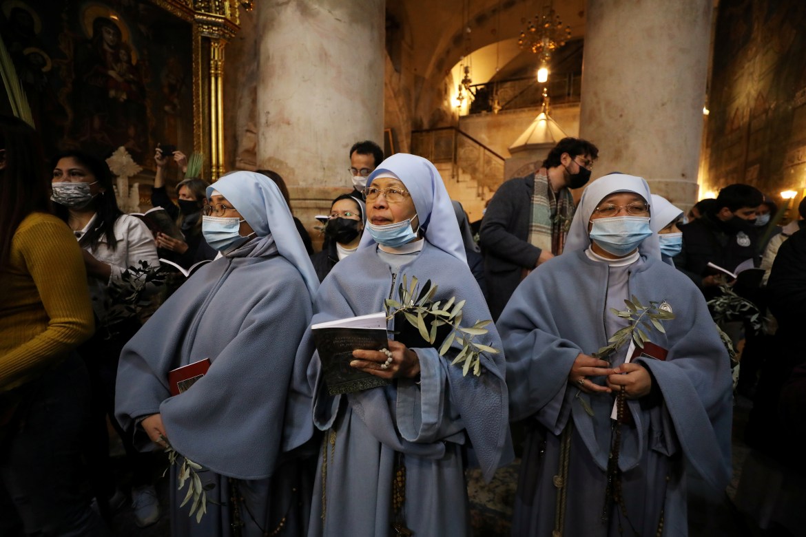 Nuns and Christian worshippers hold palm fronds during a Palm Sunday procession in the Church of the Holy Sepulchre. [Ammar Awad/Reuters]
