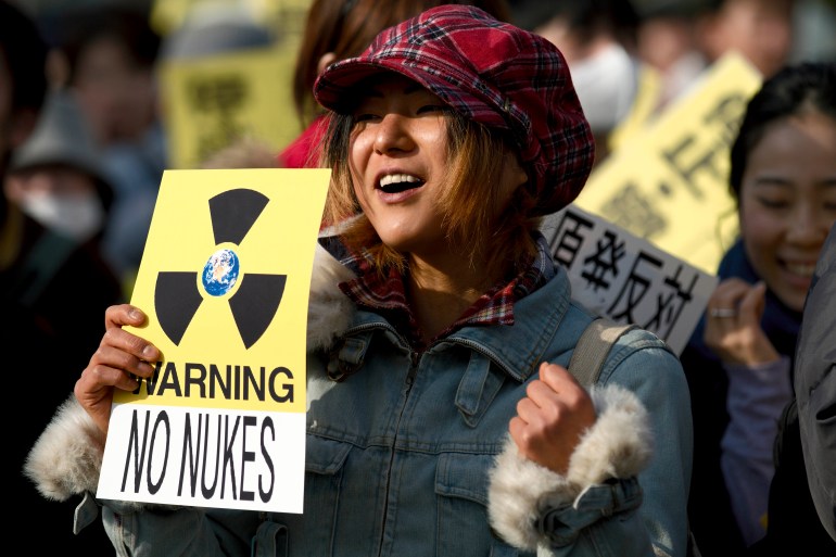 A woman holds a sign against nuclear power during an anti-war and anti-nuclear march in Tokyo, Japan