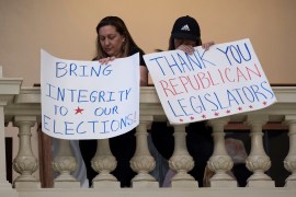 Protesters in favor of changes in Georgia's voting laws hold signs inside the State Capitol in Atlanta.