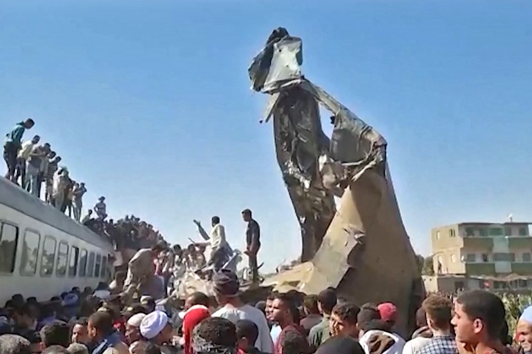 A screengrab shows people gathered around the wreckage after two trains collided in Tahta district of Sohag province on Friday [AFP]