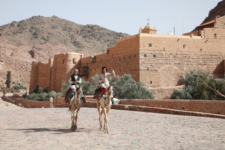 Bedouin men ride camels.