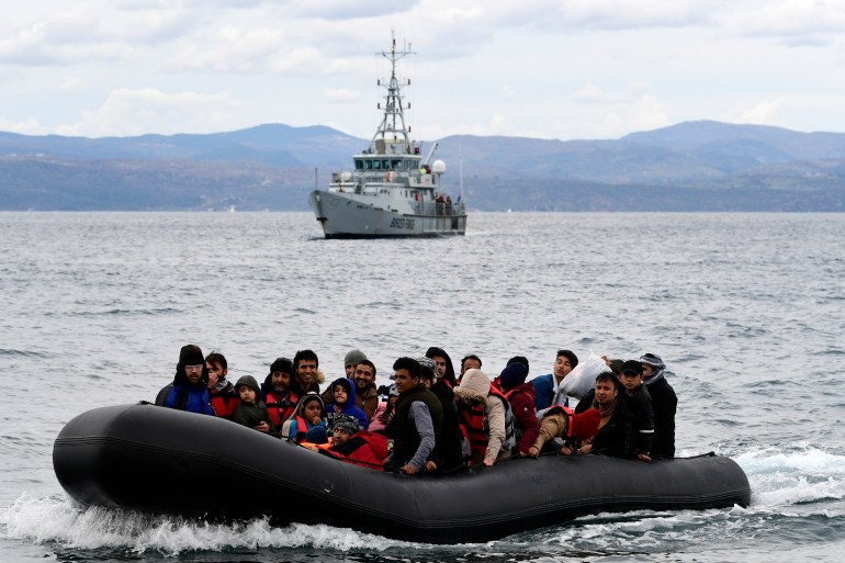 Migrants and refugees arrive in a dinghy accompanied by a Frontex vessel near the Greek island of Lesbos, after crossing the Aegean sea from Turkey in 2020