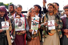 Fighters loyal to the Houthis hold up posters with the portraits of fallen comrades killed in recent battles, during a mass funeral for them at al-Saleh Mosque in Yemen&#39;s capital Sanaa on February 16, 2021 [File: AFP/ Mohammed Huwais]