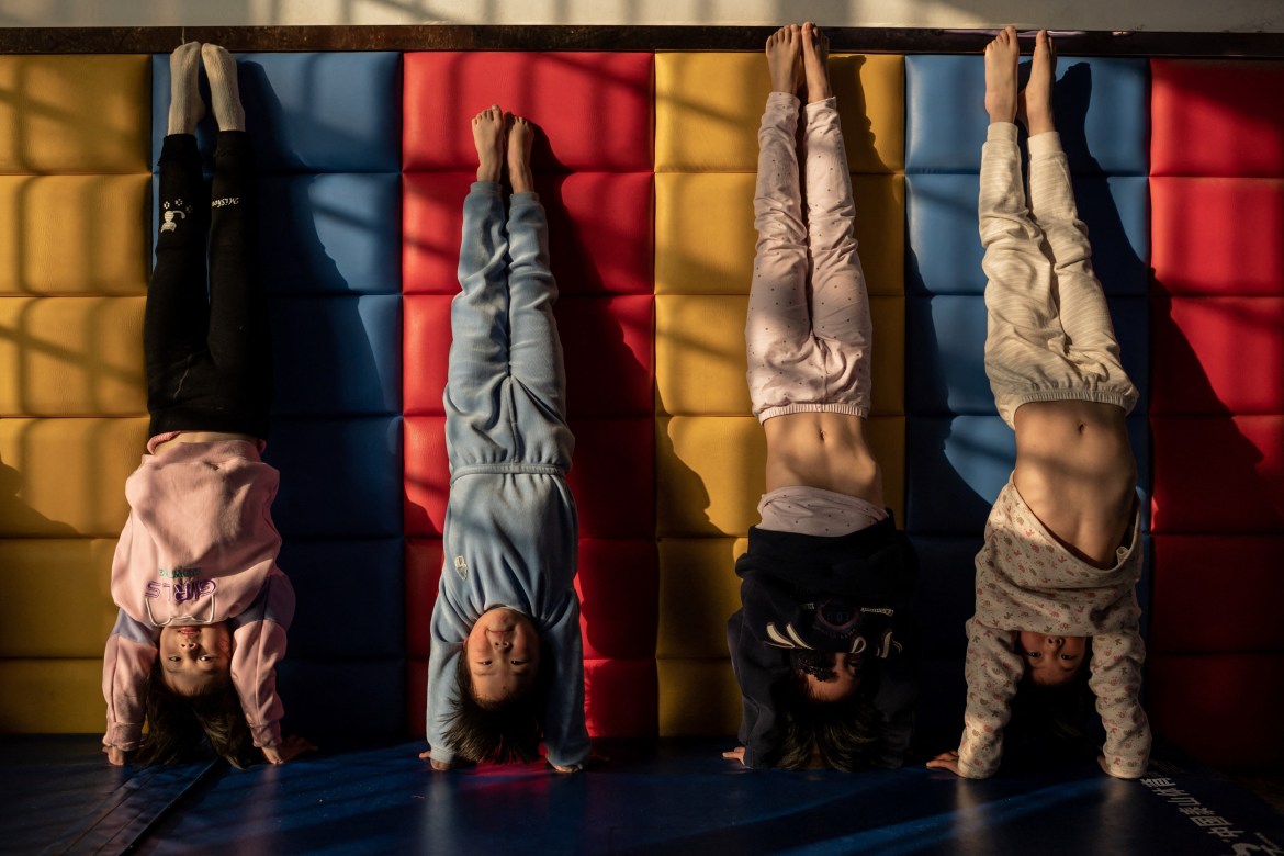 Young gymnasts train against a wall at the Li Xiaoshuang Gymnastics School. The postponed Tokyo Olympics, which are now due to start on July 23 this year, will be the defining moment for Chinese gymnasts who have trained relentlessly since as young as age four in the pursuit of gold. [Nicolas Asfouri/AFP]