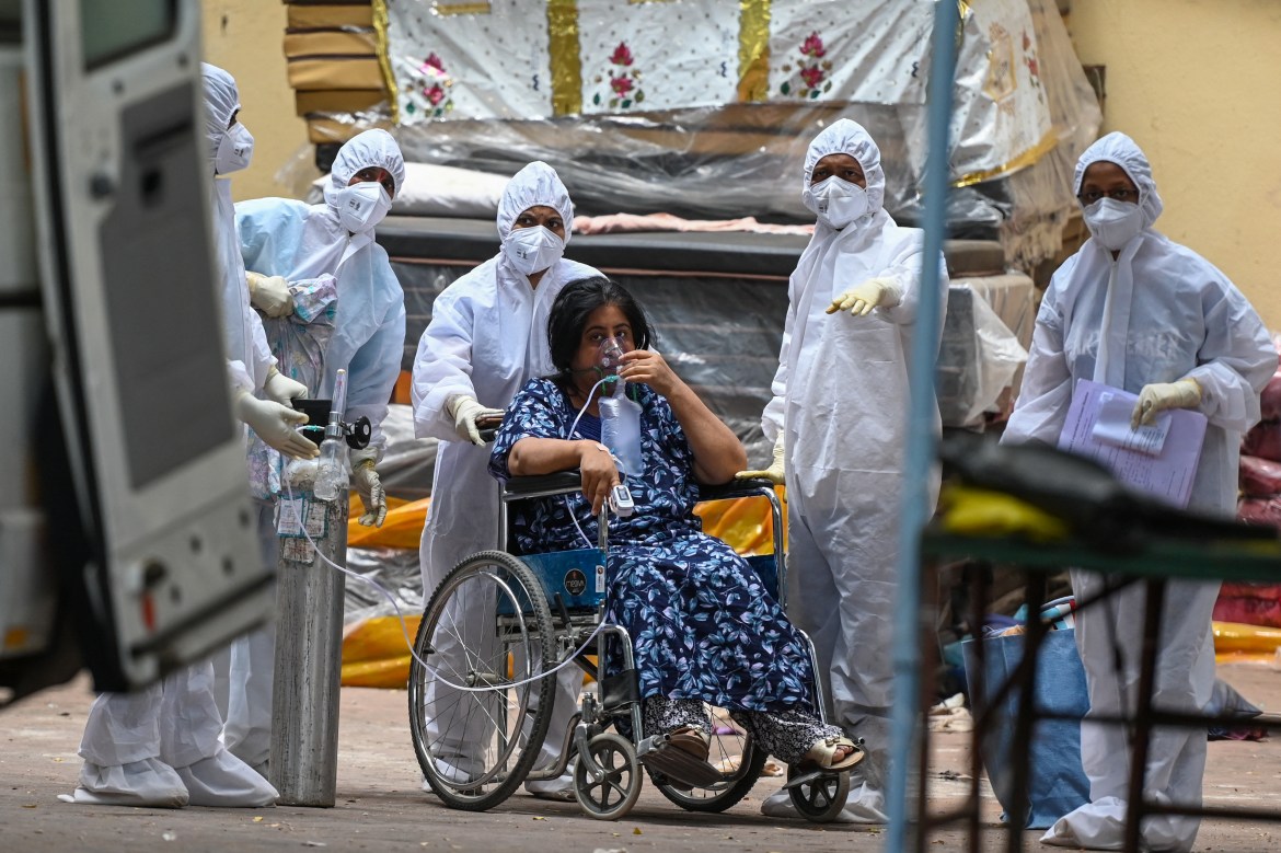 Медицинские работники стоят вокруг пациента, ожидающего перевода в отделение интенсивной терапии (ОИТ) в реабилитационном центре для лечения пациентов с коронавирусом в Мумбаи.  [Пунит Паранджпе / AFP]