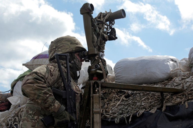 A service member of the Ukrainian armed forces is seen using a periscope while observing the area at fighting positions on the line of separation near the rebel-controlled city of Donetsk, Ukraine
