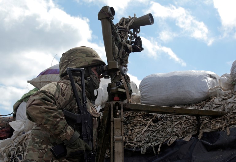 A service member of the Ukrainian armed forces uses periscopes while observing the area at fighting positions on the line of separation near the rebel-controlled city of Donetsk, Ukraine