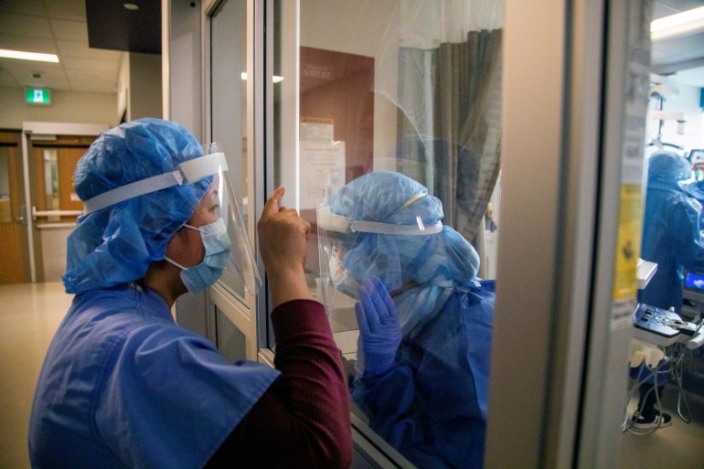 Nurses communicate through the glass door of an isolation room of a coronavirus disease