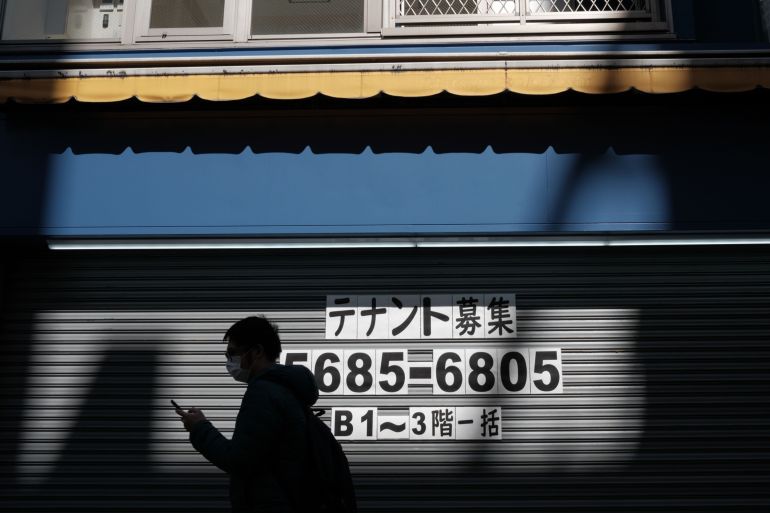 Japanese man passes closed shop during pandemic