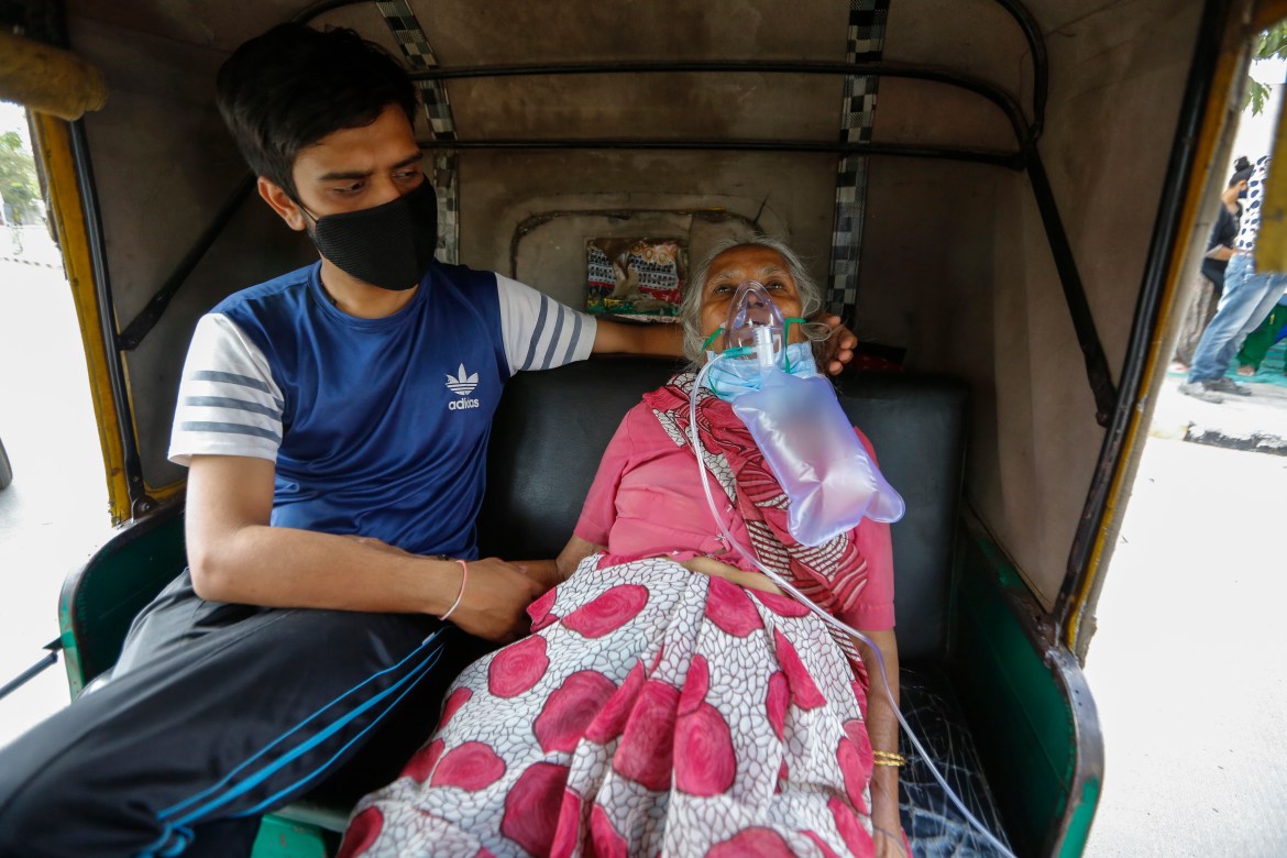 A COVID-19 patient waits inside an autorickshaw to be attended to and admitted to a dedicated COVID-19 government hospital in Ahmedabad. [Ajit Solanki/AP Photo]