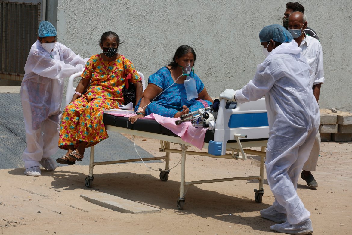 Health workers carry patients to shift them from a dedicated COVID-19 hospital to another hospital to vacate the bed for new patients, at a government hospital in Ahmedabad. [Ajit Solanki/AP Photo]