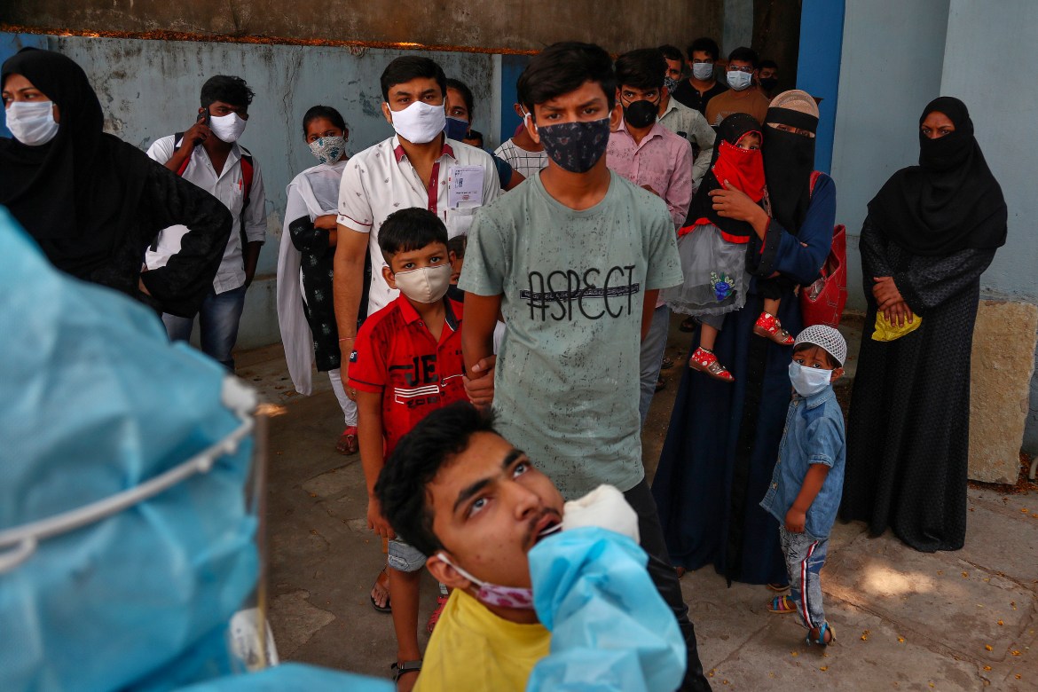 A health worker takes a swab sample to test for COVID-19 as others await their turn at a hospital in the southern city of Hyderabad. [Mahesh Kumar A/AP Photo]