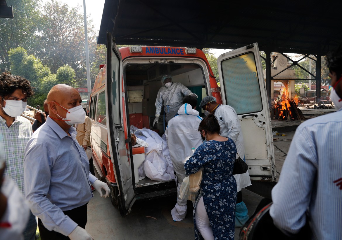 Health workers prepare to take out the bodies of six victims of COVID-19 from an ambulance for cremation in New Delhi. [Manish Swarup/AP Photo]