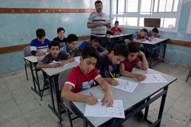 kids sitting and writing their exams in a light blue classroom of an unrwa school