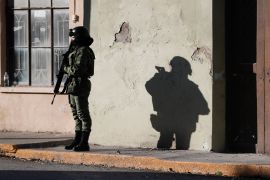A Mexican soldier stands outside of a building