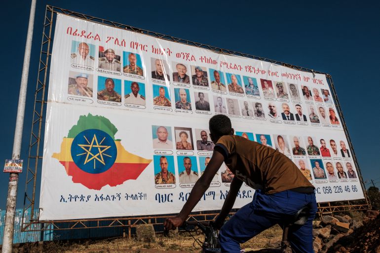 On November 26, 2020, a youngster stands in front of a sign that depicts members of the Tigray People's Liberation Front (TPLF) as wanted by the Ethiopian Federal Police and accuse them of treason