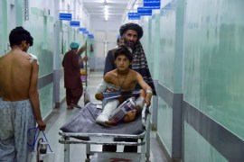 A man pushes an injured boy on a stretcher along a hospital corridor in Kandahar as he receives medical treatment after being hurt by a roadside bomb that struck a bus overnight killing at least 11 people [Javed Tanveer/AFP]