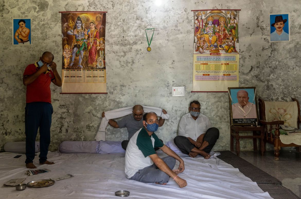 Family members sit next to the garlanded photograph of 74-year-old Rajendra Singh - who according to them died unable to access a hospital bed - at his home. [Danish Siddiqui/Reuters]