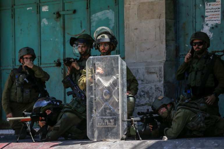 Israeli soldiers aim their weapons at Palestinian demonstrators 