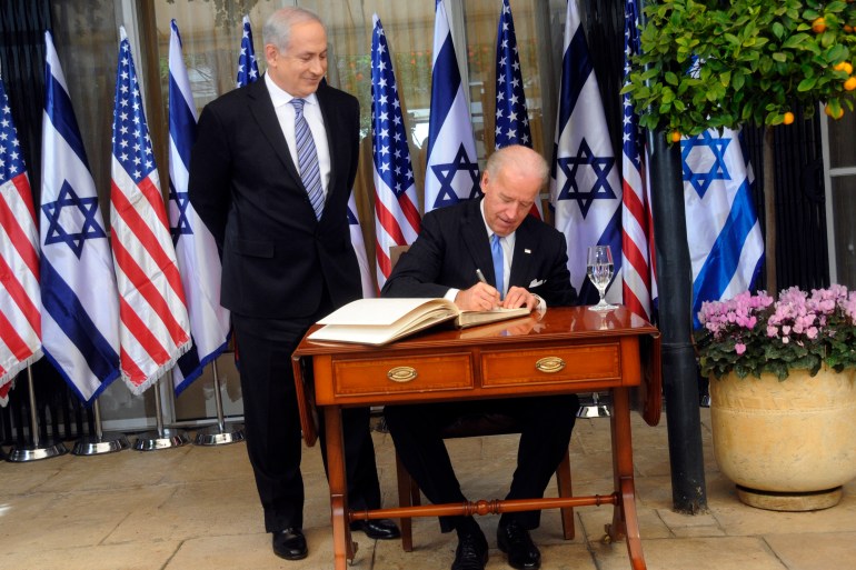 Benjamin Netanyahu, left, looks on as then-US Vice President Joe Biden signs the guest book at the then-prime minister's residence in Jerusalem, March 9, 2010