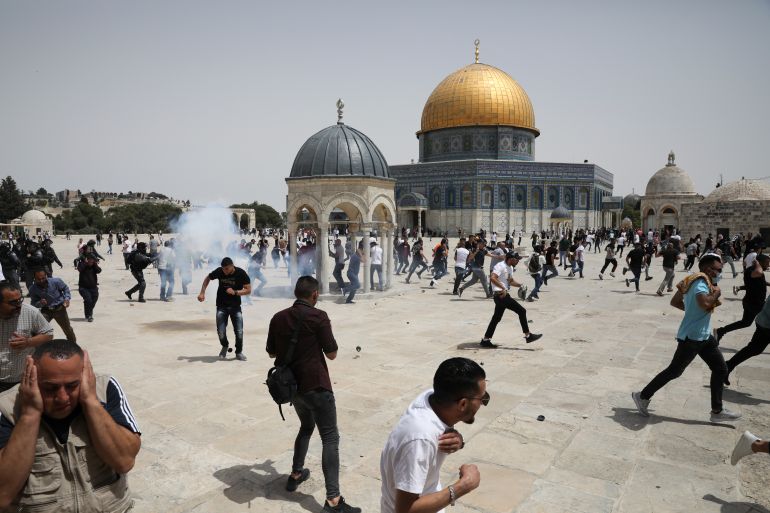 Palestinians run from sound bombs thrown by Israeli police in front of the Dome of the Rock shrine at al-Aqsa mosque complex in Jerusalem