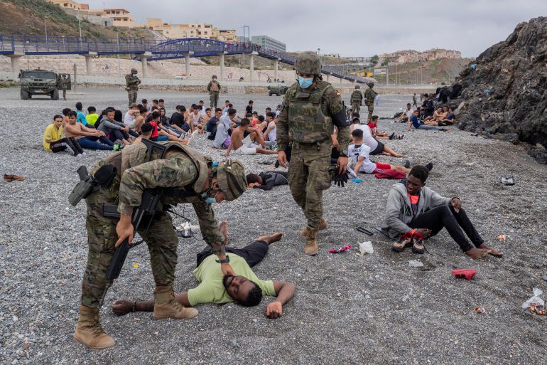A migrant is assisted by soldiers of the Spanish Army near the border of Morocco and Spain, at the Spanish enclave of Ceuta, on Tuesday, May 18, 2021. (AP Photo/Bernat Armangue)
