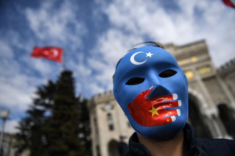 A demonstrator wearing a mask painted with the colours of the flag of East Turkestan