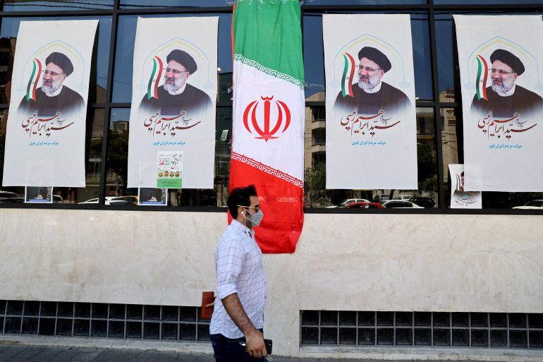 An Iranian man walks by posters of presidential candidate Ebrahim Raisi outside a campaign office in Tehran on June 7, 2021. - Iranians are set to elect a successor to President Hassan Rouhani on June 18 amid widespread discontent over a deep economic and social crisis caused by the reimposition of crippling sanctions after the US pulled out of the 2015 nuclear deal. (Photo by ATTA KENARE / AFP)