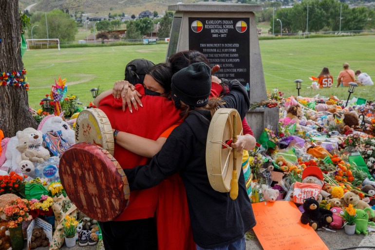 People from the Mosakahiken Cree Nation hug in front of a makeshift memorial at the former Kamloops Indian Residential School in Kamloops, British Columbia, Canada [File: Cole Burston/AFP]