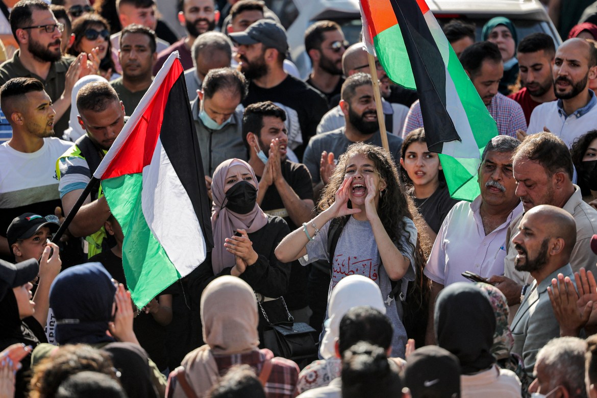 The crowd marched through streets waving Palestinian flags and pictures of Banat while calling for an end to Abbas's 16-year rule. [Abbas Momani/AFP]