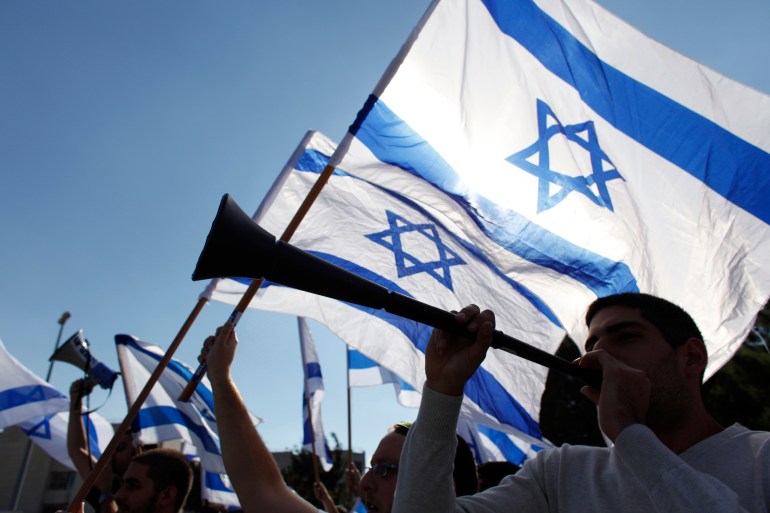 A man blows a horn as others wave Israeli flags during a demonstration supporting soldiers in Israel's military operation in Gaza, at the Hebrew University in Jerusalem November 15, 2012. A Hamas rocket killed three Israelis north of the Gaza Strip on Thursday, drawing the first blood from Israe
