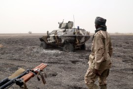 A Chadian soldier walks past an armored vehicle that the Chadian military said belonged to insurgent group Boko Haram.