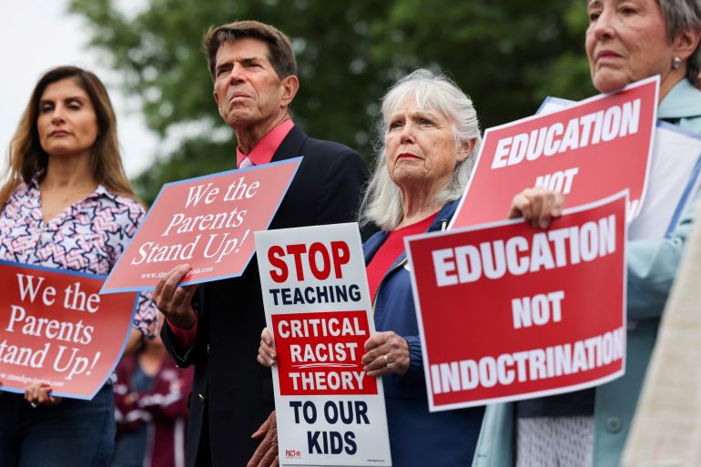 Protesters hold placards that read stop critical race theory at a rally in the US