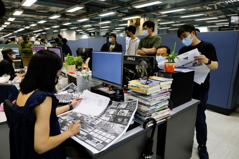 Apple Daily employees are working on the latest edition of the newspaper.  They're in the newsroom.