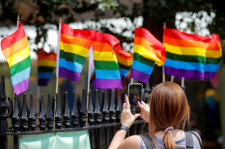 A woman photographs pride flags that celebrate Pride Month at the Stonewall National Monument at Christopher Park adjacent to The Stonewall Inn, in the Greenwich Village section of New York City, New York, U.S.