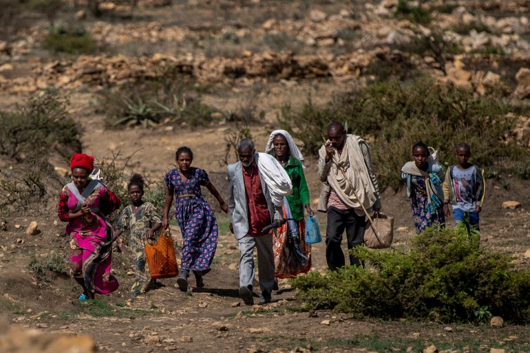 People walk from a rural area towards a nearby town where a food distribution operated by the Relief Society of Tigray was taking place, near the town of Agula, in the Tigray region of northern Ethiopia [Ben Curtis/AP Photo]