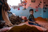 Ibrahim Al-Masri, 10, sits for a portrait in his bedroom that was damaged by Israeli bombardment. May 26, 2021, Beit Hanoun, Gaza Strip. [John Minchillo/AP]