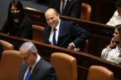 Israel&#39;s designated new prime minister Naftali Bennett sits behind outgoing Prime Minister Benjamin Netanyahu during a Knesset session in Jerusalem on June 13, 2021 [AP/Ariel Schalit]