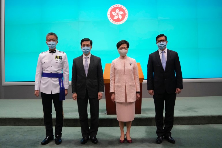 Hong Kong's Chief Executive Carrie Lam, second right, poses with Chief Secretary John Lee on the day he was promoted to No. 2 in June 2021