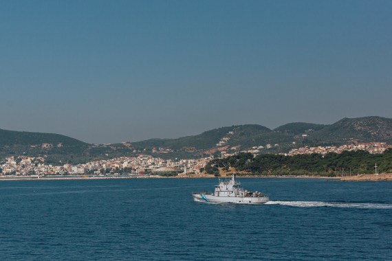 A Greek coast guard vessel sails in front of the shoreline of the city of Mytilini, Lesvos
