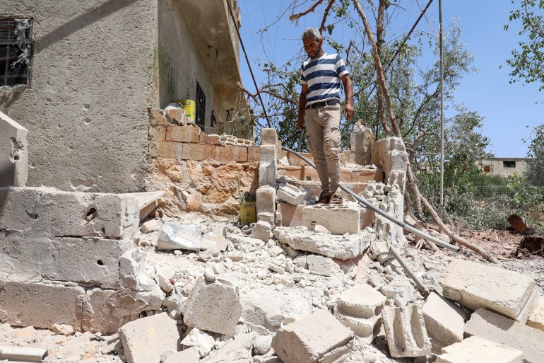 A Syrian man inspects a damaged house