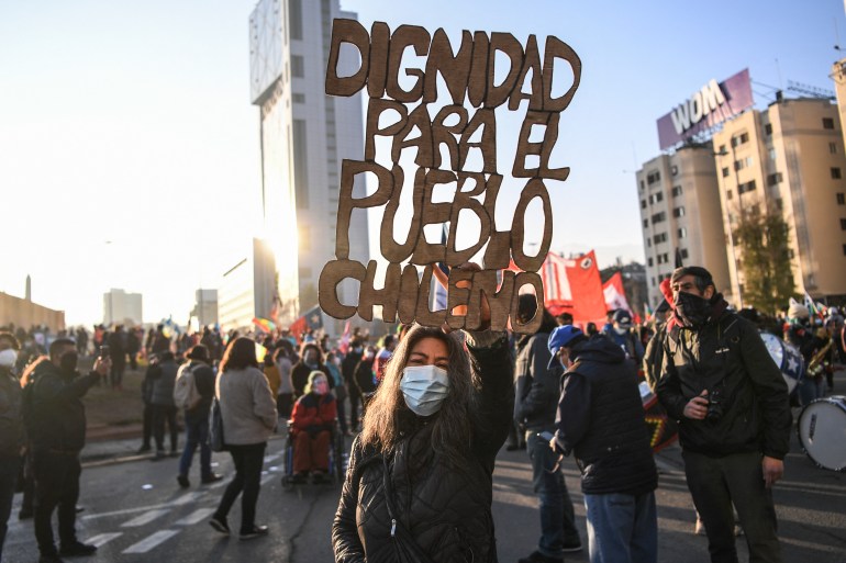 A demonstrator holds a sign reading 'Dignity for Chilean people' during a march towards the Chilean National Congress where the Constituent Assembly will be inaugurated in Santiago, on July 4 [Martin Bernetti/AFP]