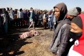 People stand around the body of a 12-year old boy allegedly shot by taxi drivers outside Chris Hanni Mall in Vosloorus, on July 14, 2021 [AFP/Guillem Sarorio]