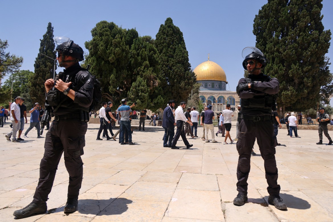 Israeli security forces stand guard as a group of Orthodox Jews enter the Al-Aqsa Mosque compound in Jerusalem during the annual Tisha B'Av (Ninth of Av) fasting and memorial day, commemorating the destruction of ancient Jewish temples some 2,000 years ago. [Ahmad Gharabli/AFP]
